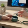 Hands remove a teal Audionic Airbud 725 Pro earbud from its charging case, connected by a C-Type cable on a desk.