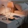 Audionic Tesla T10 10000mAh power bank charging a smartphone on a bedside table next to a warm lamp.