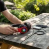 Hands hold red Cats Ear Wireless Headphones with RGB paw print, charging on wooden table with power bank and phone outdoors.