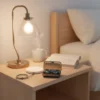 F9 Airdots Pro wireless Bluetooth earbuds in power bank case on bedside table with lamp, coffee, and charger.