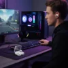 Man wearing Mars Elite Series E-52 wireless earbuds at PC gaming setup. Earbuds charging case open on desk.