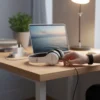 White P47 Wireless Bluetooth Stereo Headphones on a wooden desk, hand holding cable by a laptop.
