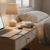 Silver PB22 Super Powerbank 20000mAh 100W PD charging laptop on a bedside table with earbuds.